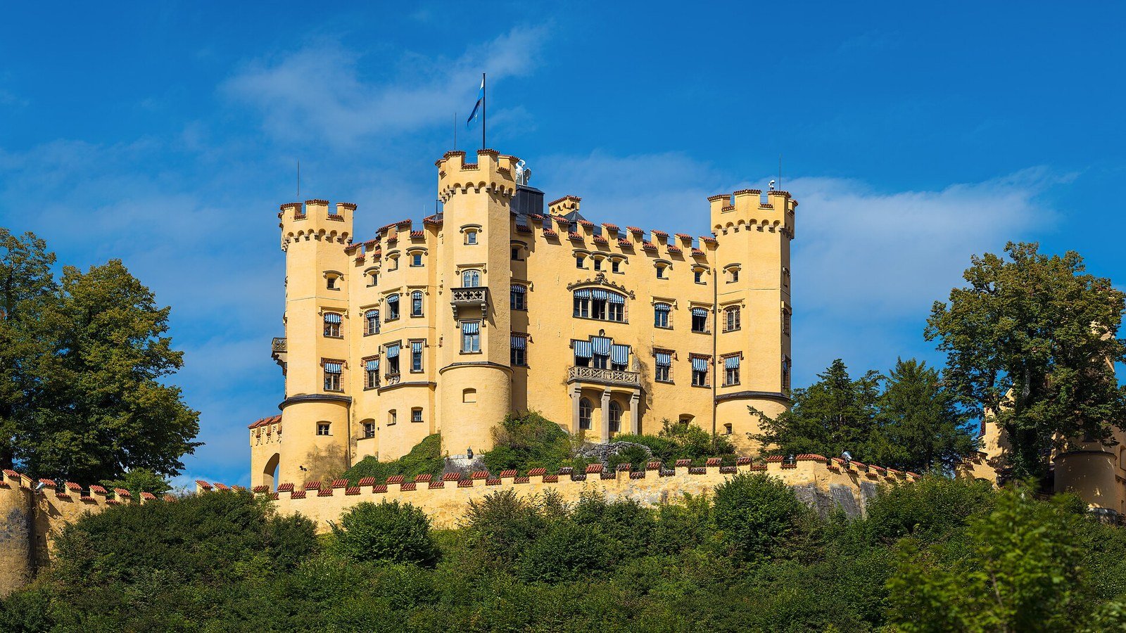 Hohenschwangau Castle yellow facade with Alpsee lake in foreground