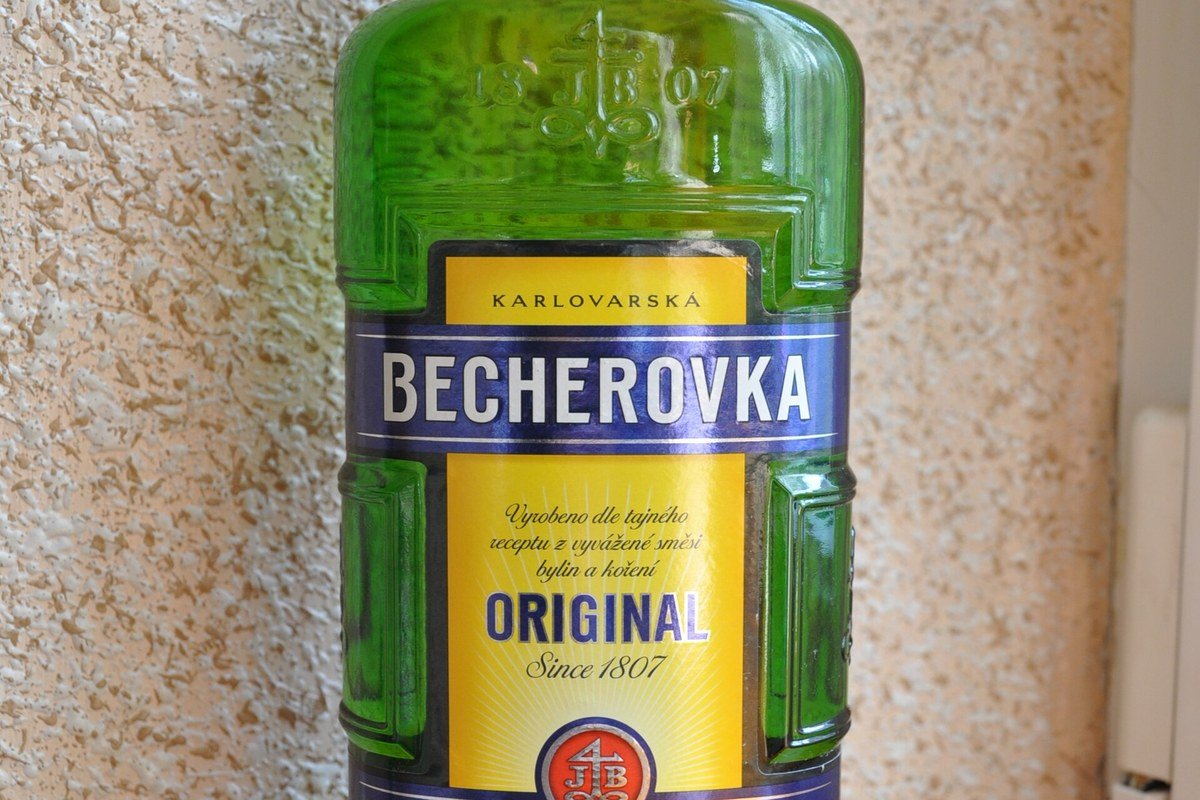 Becherovka herbal liqueur bottle with two glasses on a wooden table